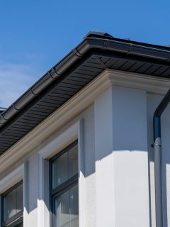 White two story house with black steel roofing and black gutters, Are Home Gutters Necessary In Texas?