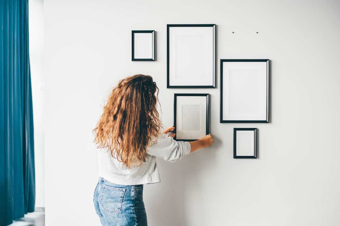 Woman hanging a frame on a wall