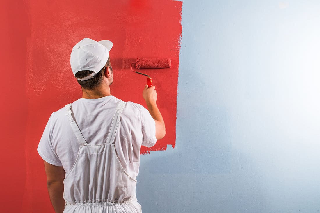 Young man painting wall with roller