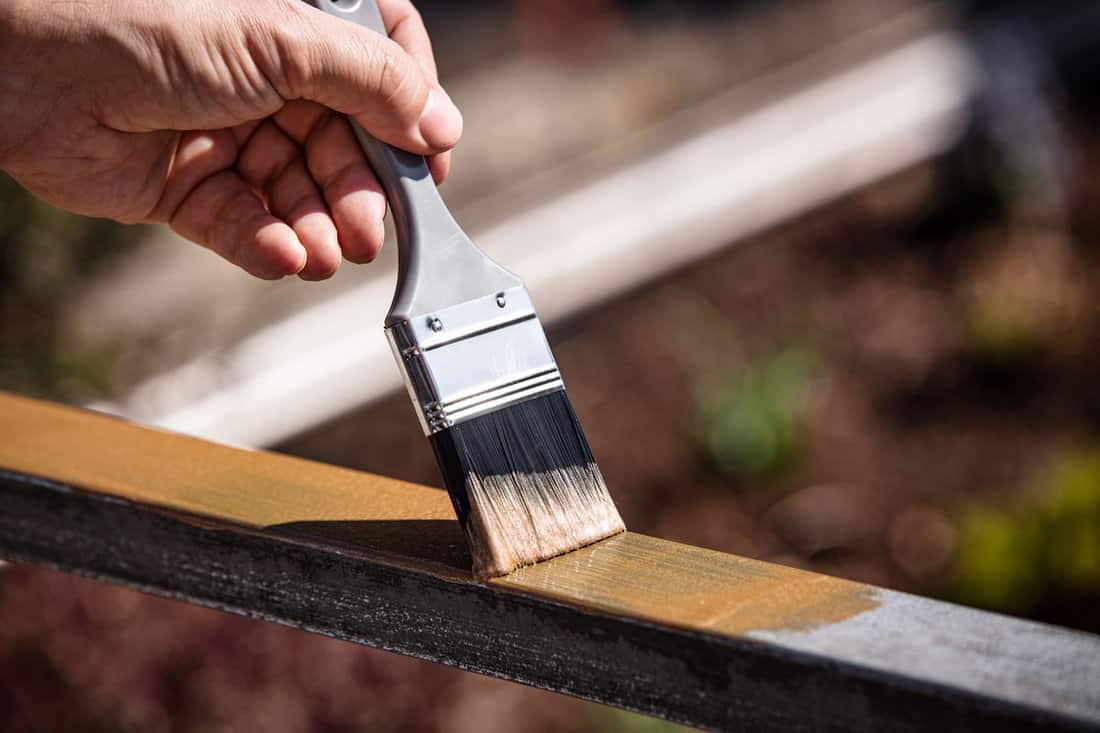 a man is painting a metal railing with copper varnish
