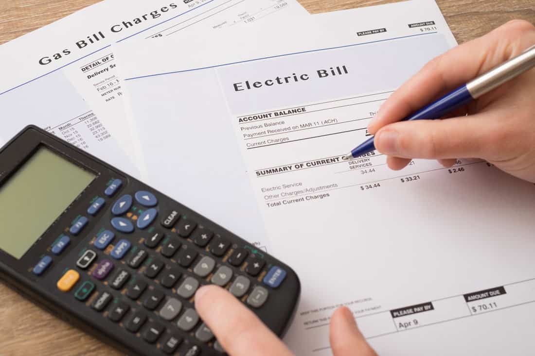 close up photo of an electric bill paper documents and a calculator calculating bills