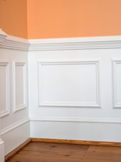 white wainscoting and chair rail on wall of orange peach dining living room of colorful home house - How High Should Wainscoting Be