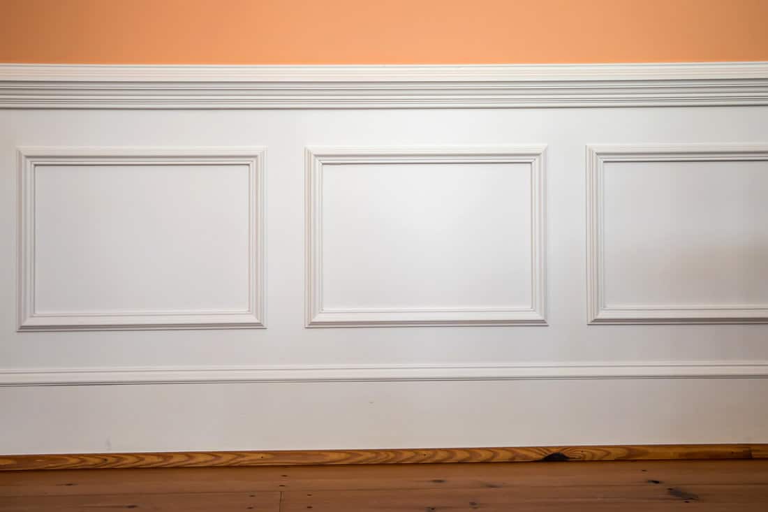 white wainscoting and chair rail on wall of orange peach dining living room of colorful home house