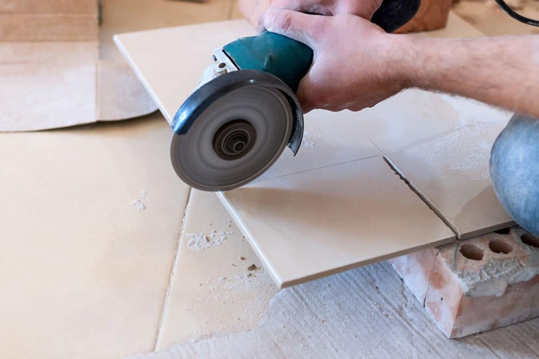 A construction worker cutting a tile using an angle grinder