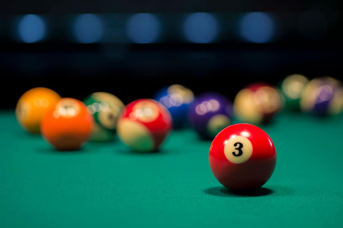 American pool balls on a pool table with number three in focus