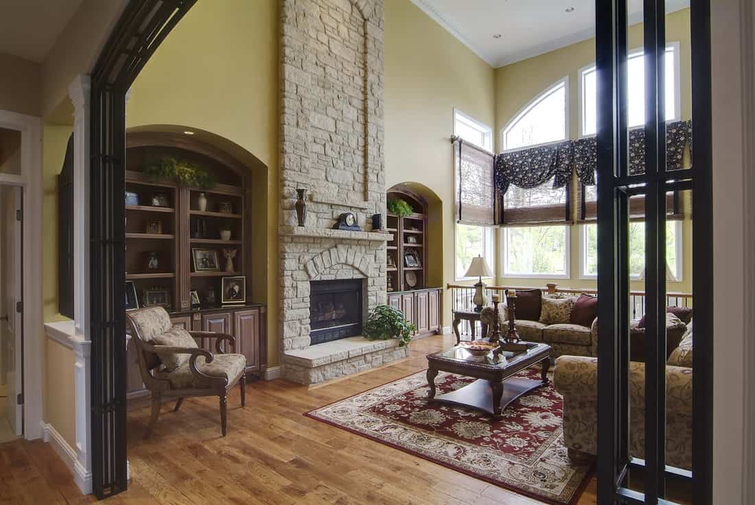 An old-fashioned living room with open wall entrance and stone fireplace