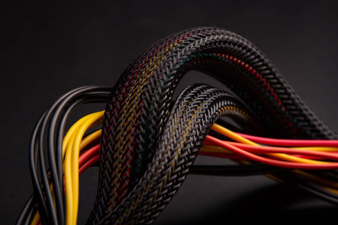 Cable snake skin. Black braided wires in bundle on black background