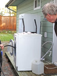 Canadian father and son check water drainage on old washing machine outside their house in winter. DIY project. - How To Run A Washing Machine Drain Outside Into The Yard