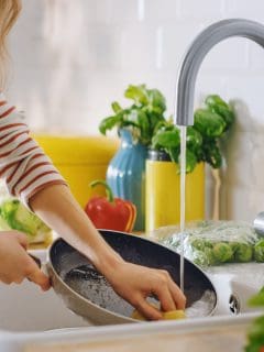 Close Up Shot of a Woman Washing a Frying Pan with a Cleaning Liquid Under Tap Water. Using Dishwasher in a Modern Kitchen. Natural Clean Diet and Healthy Way of Life Concept.How To Clean Pans With Burnt Bottoms [Do This!]