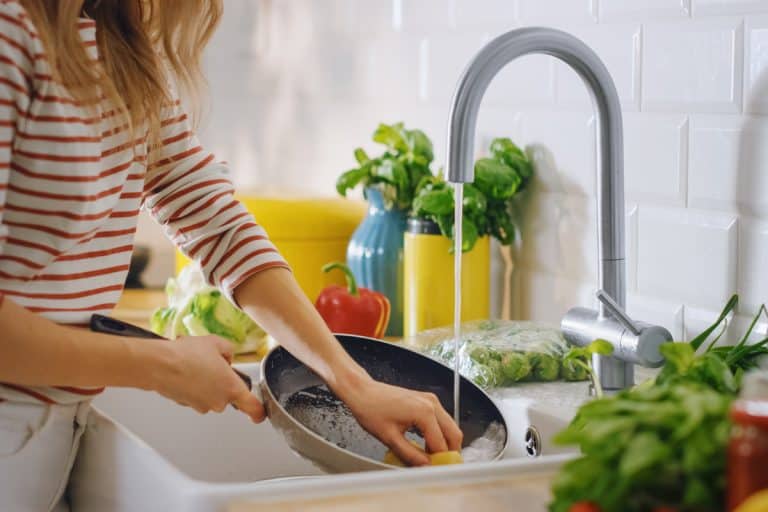 Close Up Shot of a Woman Washing a Frying Pan with a Cleaning Liquid Under Tap Water. Using Dishwasher in a Modern Kitchen. Natural Clean Diet and Healthy Way of Life Concept.How To Clean Pans With Burnt Bottoms [Do This!]