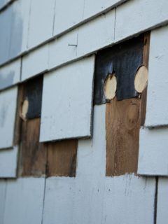 Close up of exterior suburb house siding repair of missing blue wood shingles under construction remodeling - How To Replace Siding On A House [Step By Step Guide]