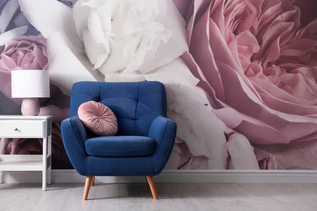 Comfortable armchair near wall with floral wallpaper