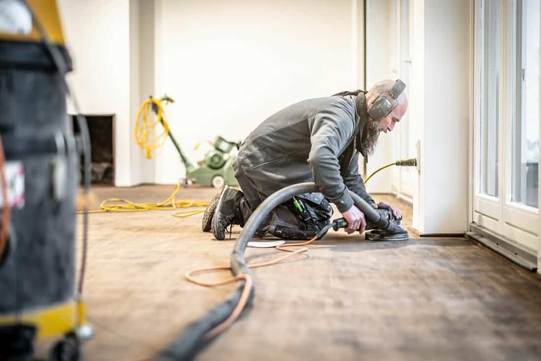 Craftsman grinds the parquet floor with the edge grinder