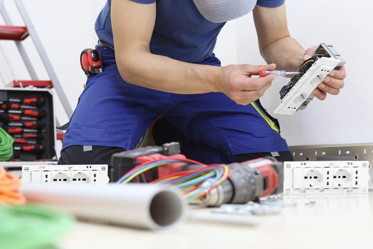 Electrician at work with socket in hand installing electric circuits, Rewiring A House DIY - Here's What You Need To Know!