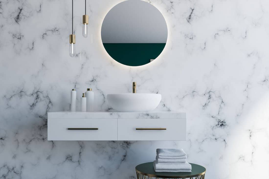 Elegant white sink standing on a white shelf. A round mirror is hanging above it. White marble bathroom interior. 3d rendering mock up