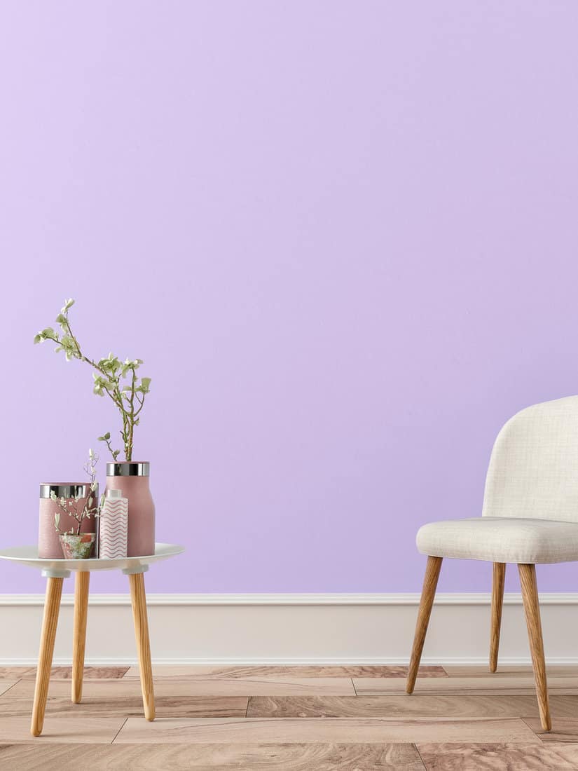 Empty retro interior on lavender plaster wall background on hardwood floor with copy space and decoration. Slight vintage effect added.