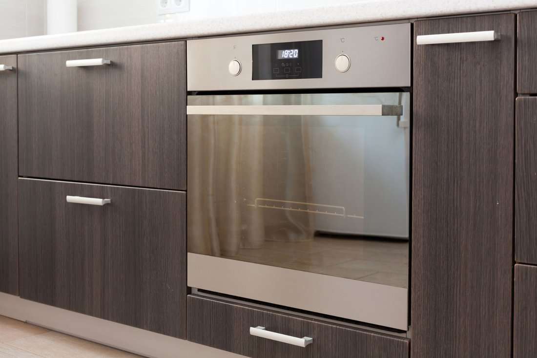 Kitchen cabinets with metal handles and built-in electric oven