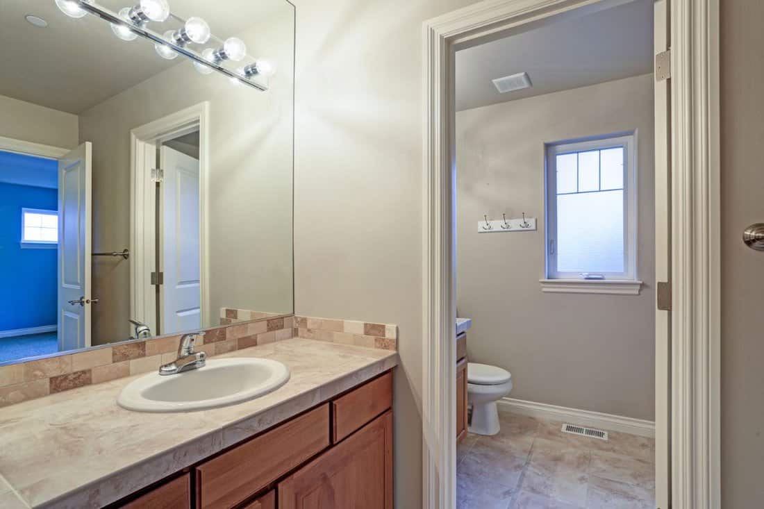 Light bathroom interior with view of vanity cabinet, toilet and small window