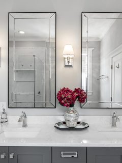 A luxurious bathroom with a grey double vanity with flowers sitting on the white quartz counter top, How To Vent A Double Vanity [Step By Step Guide]