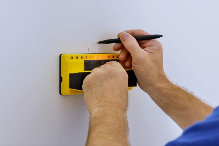Man scanning wall to find find studs more accurately through difficult surfaces, How To Use A Franklin Sensors Stud Finder [Step By Step Guide]
