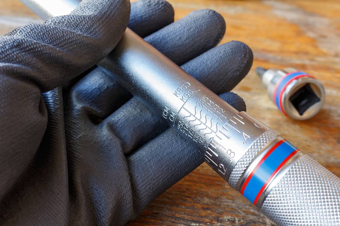 Mechanic's hand in the working glove holds the torque wrench