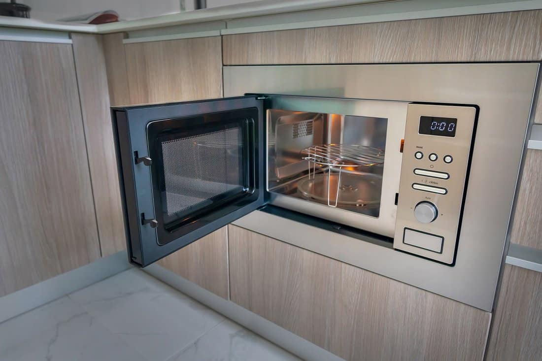Open microwave oven in kitchen, microwave built into kitchen design creates a seamless integration.