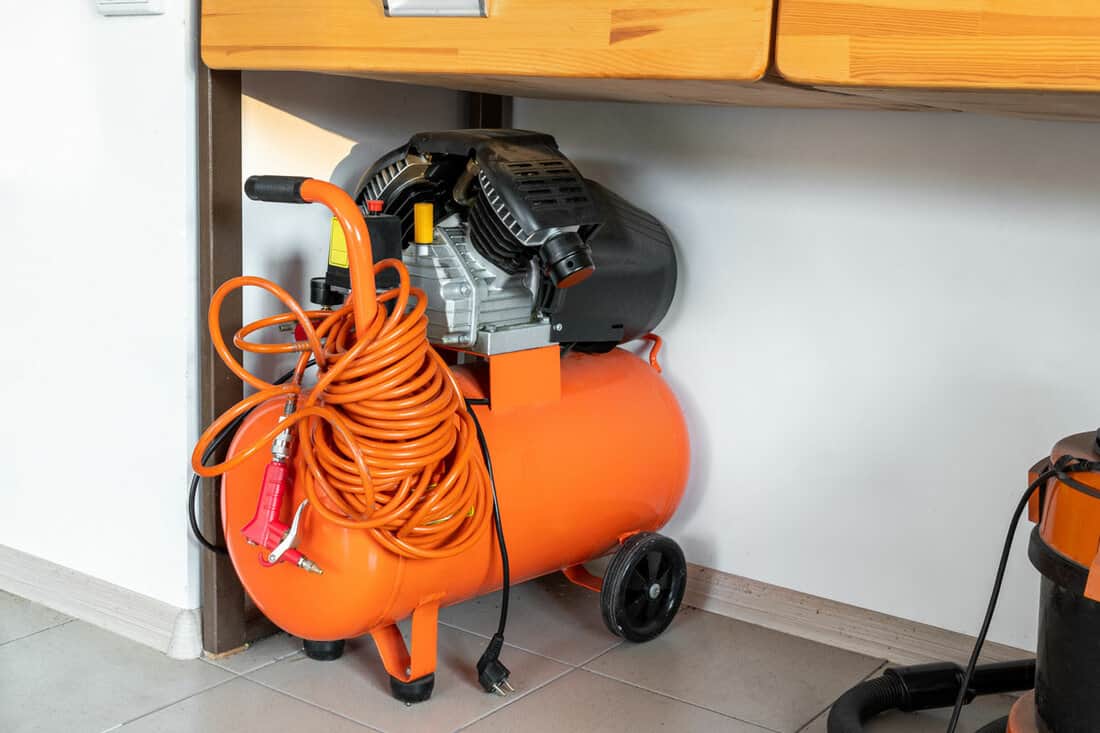 Orange small portable industrial power air compressor with coil hose