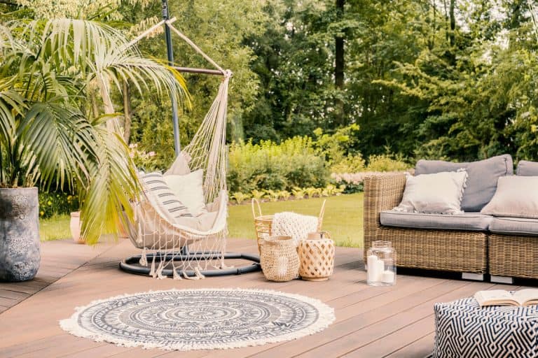 Pillows on hammock on terrace with round rug and rattan sofa in the garden. Real photo, How To Remove Mold From An Outdoor Rug?