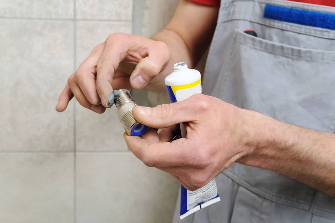 Plumber putting a paste sealant on the thread of a pipe