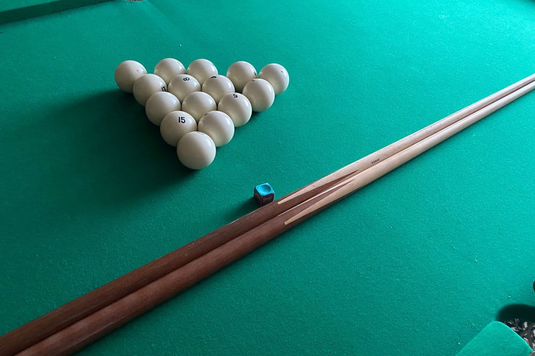 Pool cues and balls on a green table side view