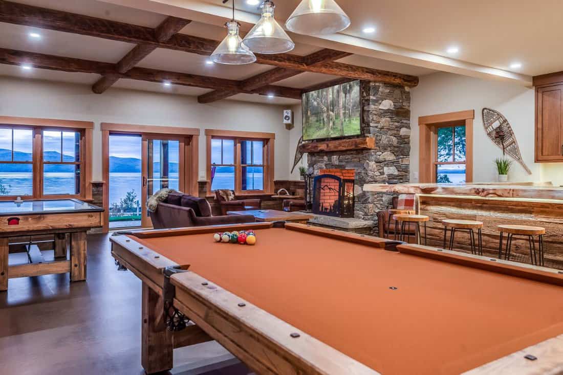 Pool table, bar and tv watching area with a large stone fireplace