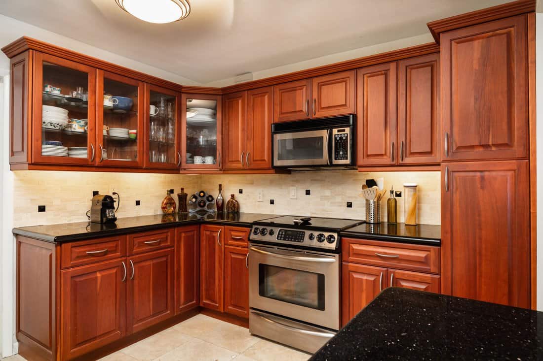 Traditional cheery wood cabinet home kitchen with a black granite countertop