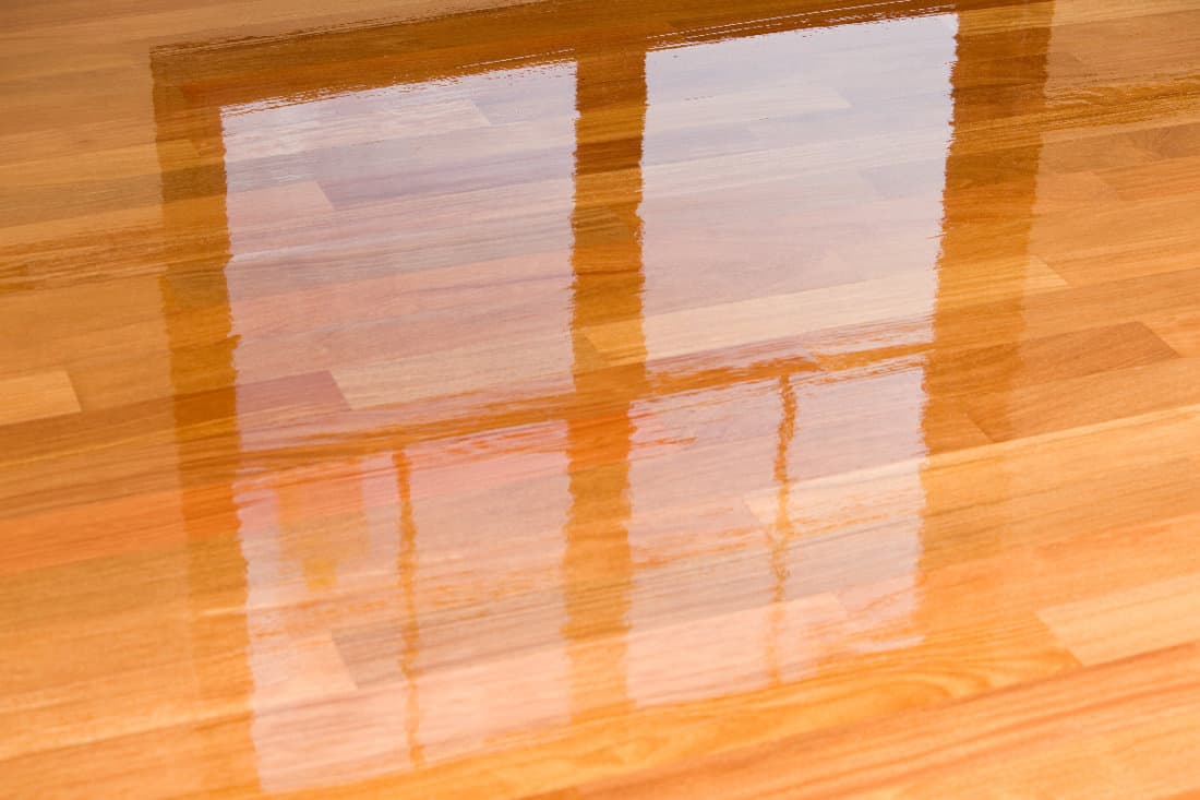 Wet polyurethane on new hardwood floor with window reflection