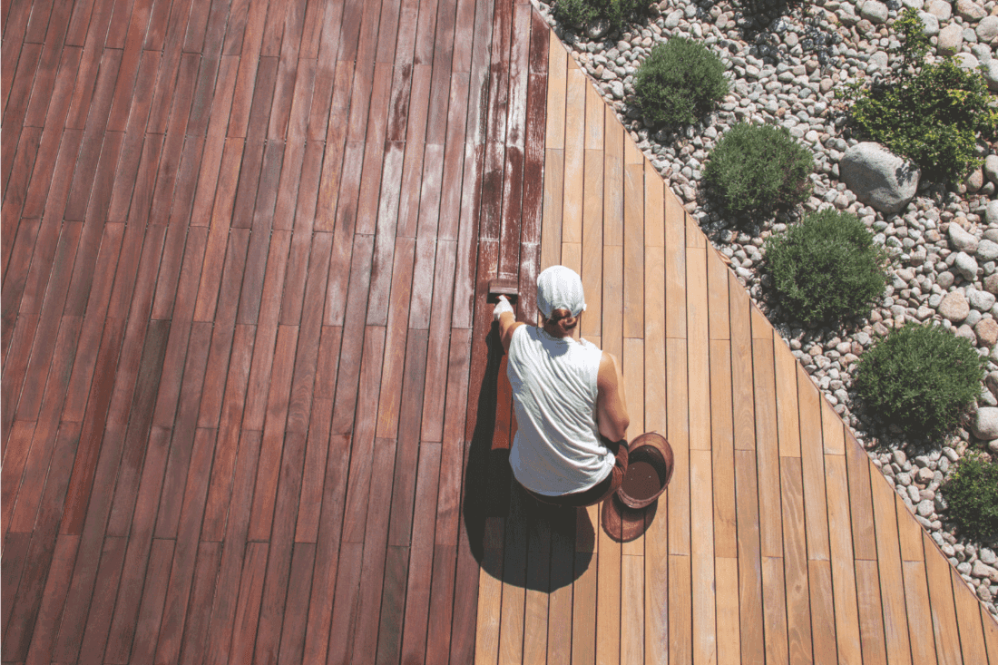 Wood deck renovation treatment, the person applying protective wood stain with a brush