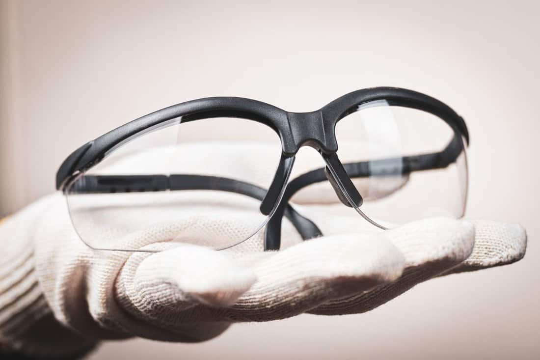 Worker's hand giving safety glasses: concept of eye protection and preservation of vision.