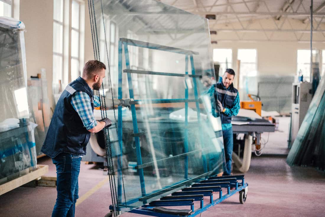 Workers packaging glass sheets in warehouse