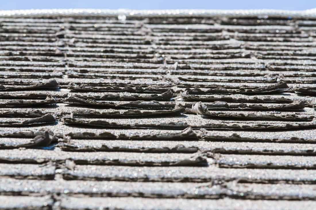 Worn-out asphalt shingles on a roof; shingles needing replacement or repair