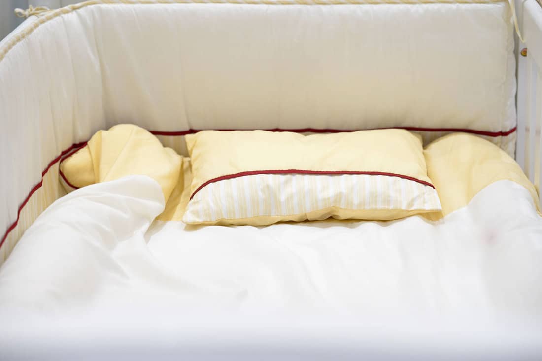 empty-baby-crib-mattress-bed yellow pillow case