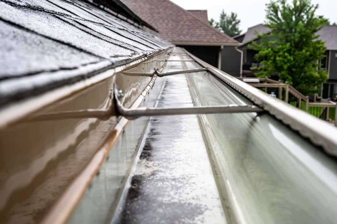 section of residential guttering with hanger conveying water during a storm