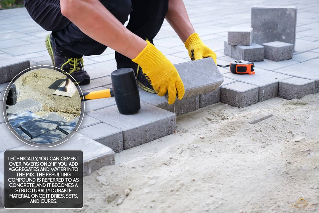 The master in yellow gloves lays paving stones in layers. Garden brick pathway paving by professional paver worker. Laying gray concrete paving slabs in house courtyard on sand foundation base., Can You Cement Over Pavers?