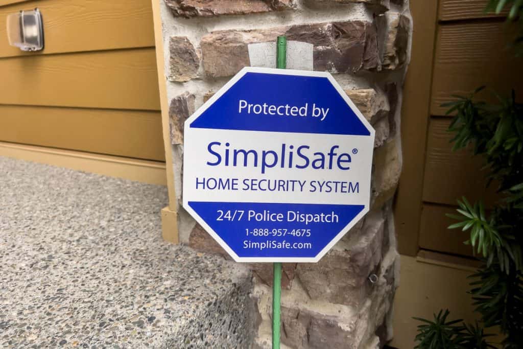 A SimpliSafe sign outside a house intended for marketing