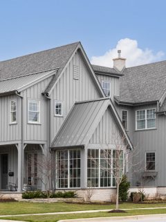 A large gray modern farmhouse with a covered front porch, large windows, and board and batten siding, How Thick Should Board & Batten Boards Be?