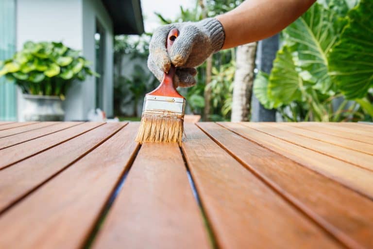 A man holding brush and painting on the wooden table, Do You Need To Prime Wood Before Staining?