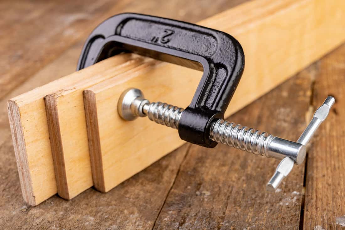 A small joinery clamp used for gluing planks. Accessories for carpenters on the workshop table