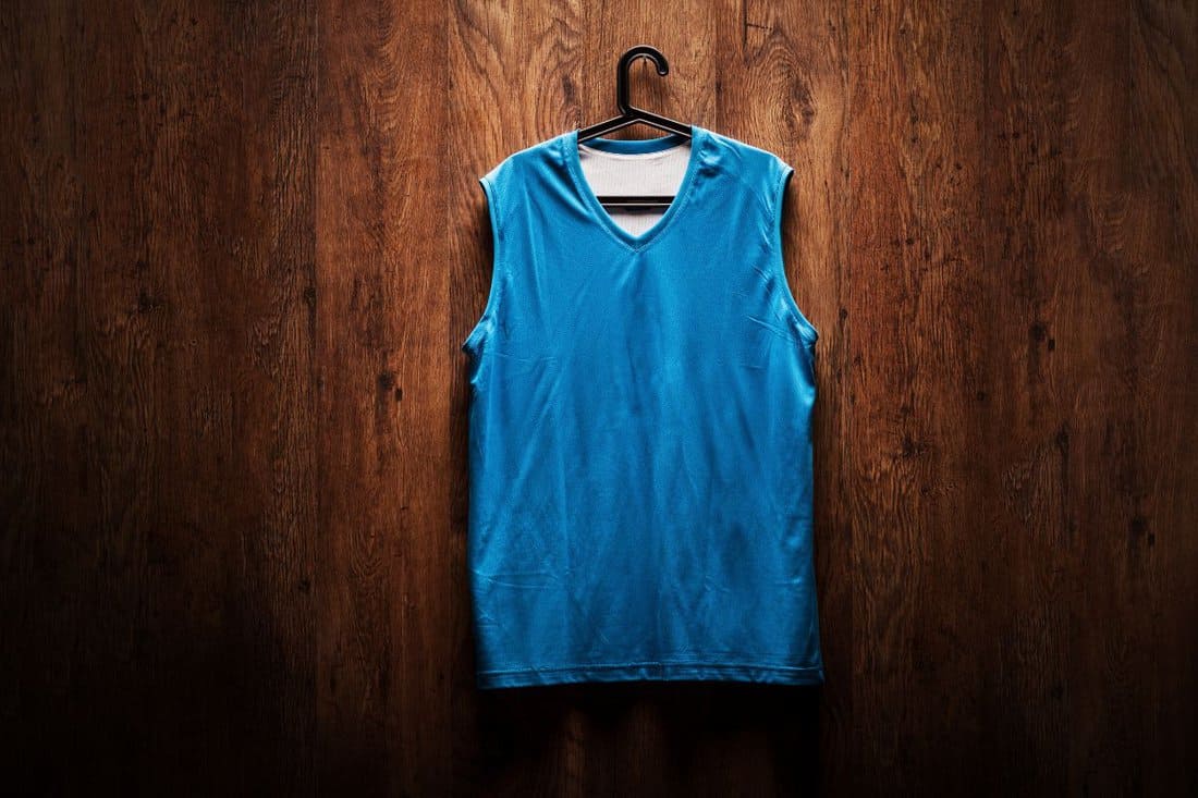 Blue basketball jersey hanging on a wooden wall on a hanger 