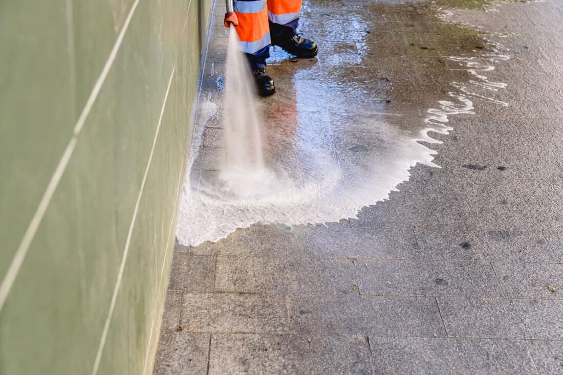 Cleaning worker throwing pressure water to clean the sidewalks of a city