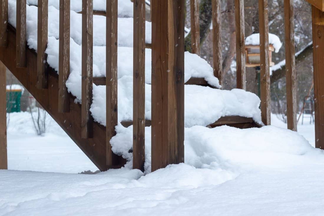 Full frame texture background of deep snow accumulation on a residential wooden deck stairs following a blizzard.