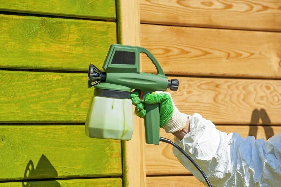 Hand painting wooden wall with spray gun in green 