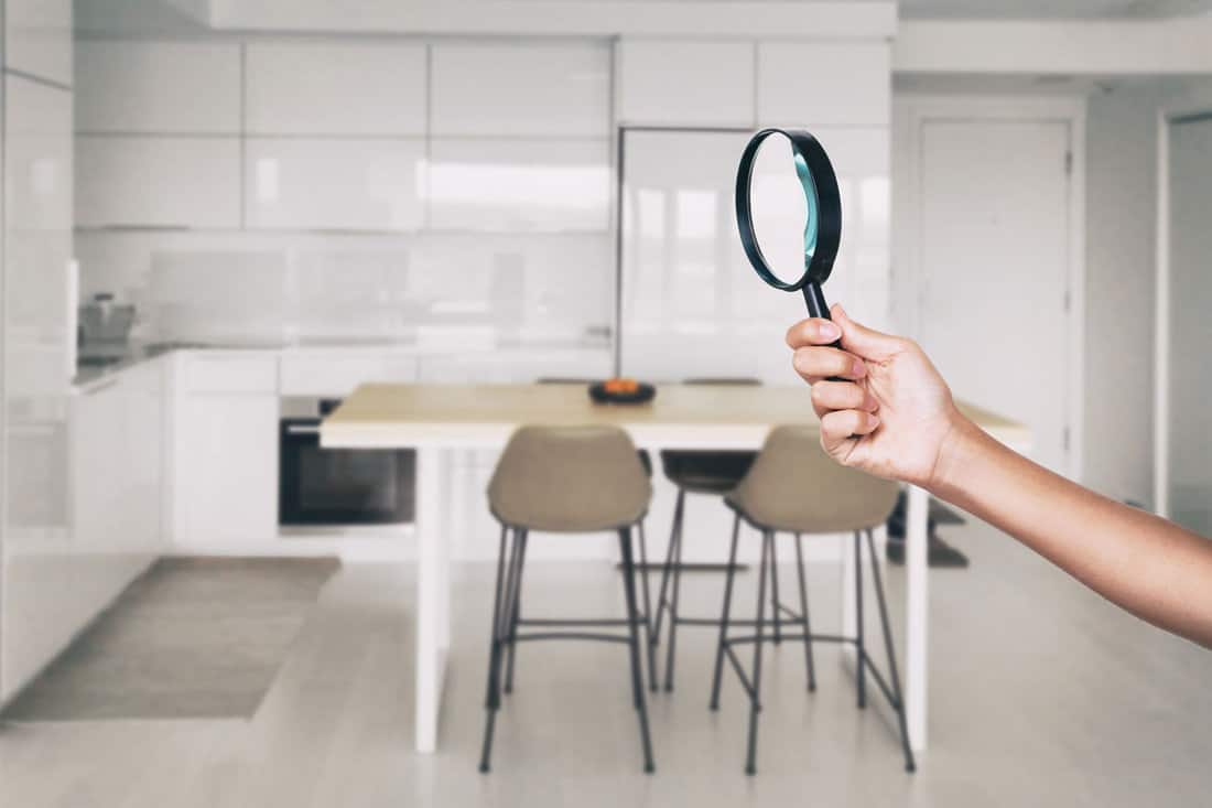 Home inspection - magnifying glass inspector looking at kitchen house
