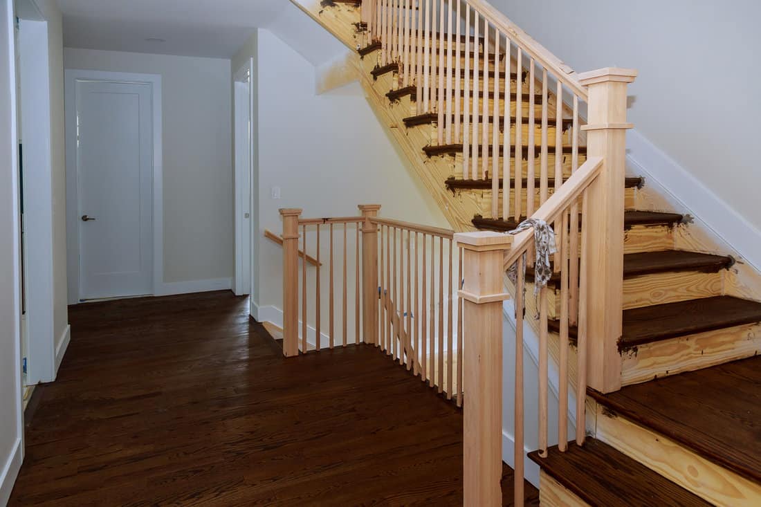 Home new construction staining with stains staircase with wood railings and hardwood floors. 